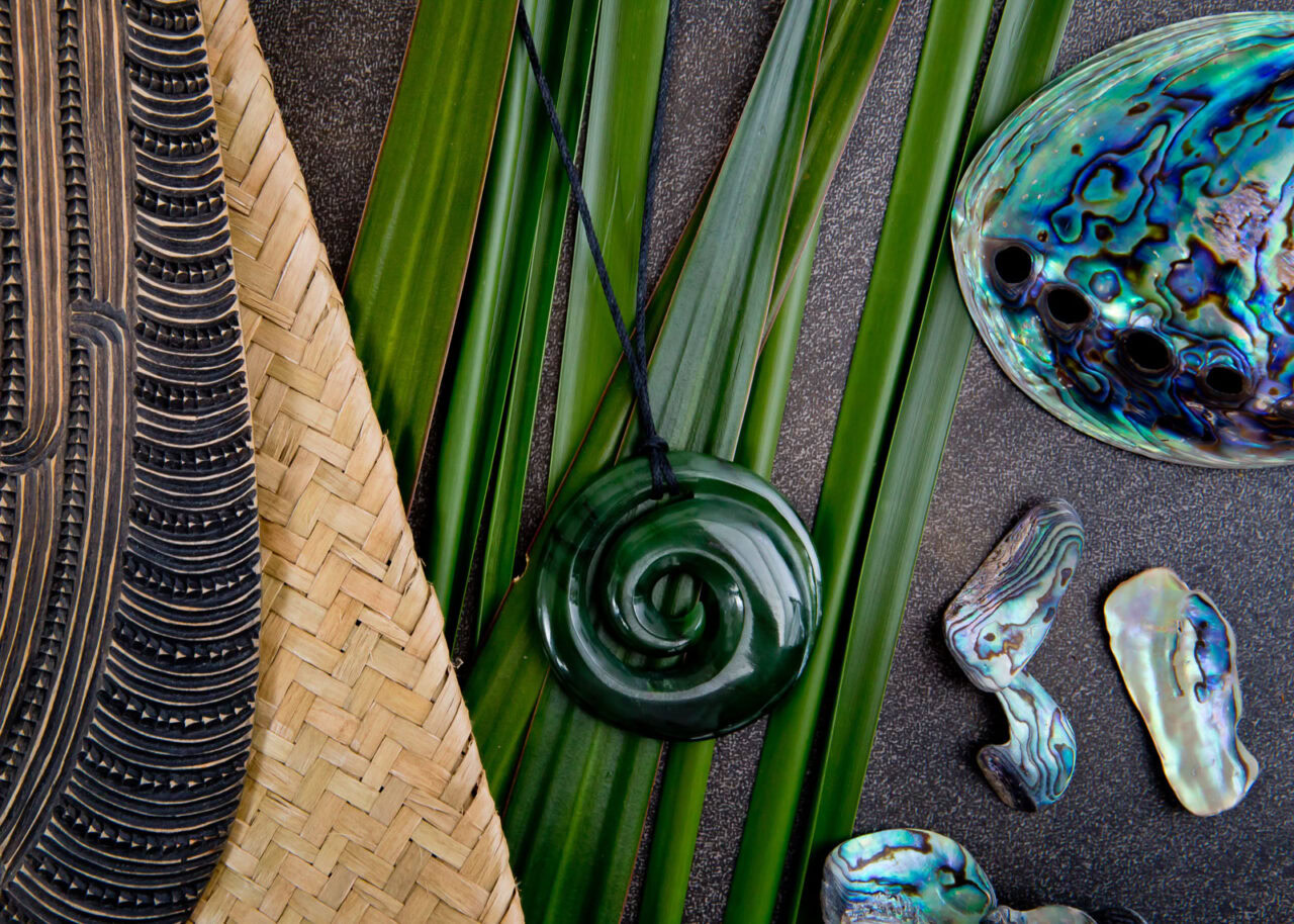 Jade jewelry and paua shells on gray stone background